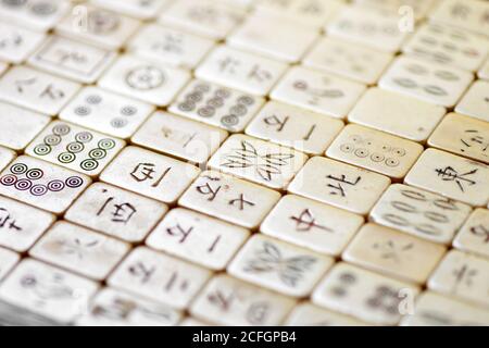 Nahaufnahme von alten Mahjong-Kacheln mit chinesischer Schrift in Eine schräge Winkelansicht mit selektivem Fokus zur Mitte Stockfoto