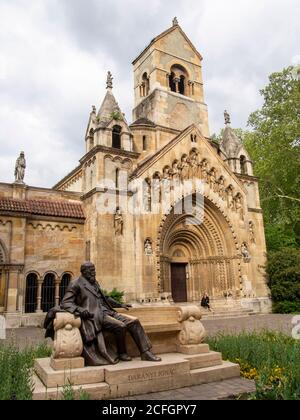 Leben imitierende Kunst: Kirche im Stadtpark mit Statue von Daranyi Ignac vor. Eine Frau sitzt in ähnlicher Pose auf der Kirchentreppe. Stockfoto