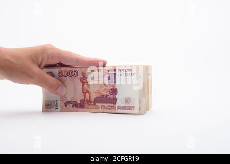 Hand hält ein Bündel von Banknoten, fünftausend Scheine auf weißem Hintergrund Stockfoto