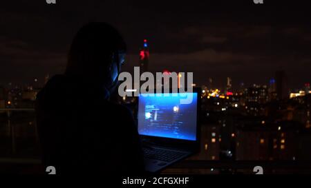 Frau, die nachts auf der Terrasse einen Laptop benutzt Stockfoto