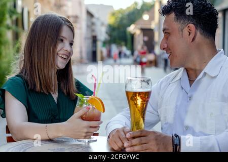 Multirassisches Paar auf einem ersten Termin auf der Straßenterrasse des Cafés. Freundschaftskonzept mit jungen, multiethnischen Menschen, die Zeit miteinander genießen. Stockfoto