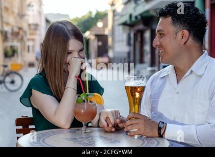 Multirassisches Paar auf einem ersten Termin auf der Straßenterrasse des Cafés. Freundschaftskonzept mit jungen, multiethnischen Menschen, die Zeit miteinander genießen. Stockfoto