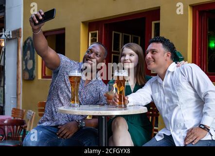 Multirassische Gruppe von Freunden trinken und Selfie auf der Straßenterrasse des Cafés. Freundschaftskonzept mit jungen multiethnischen Menschen genießen Zeit Stockfoto