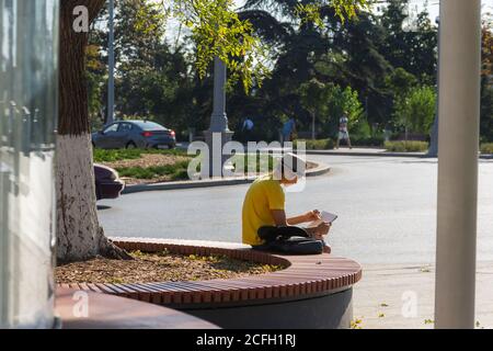 Ein Junge zieht sich auf den Uschakow-Platz in Sewastopol am 13. August 2020. Ein junger Künstler zeichnet eine urbane Landschaft. Der Künstler ist Linkshänder. Ein Junge in einem Hut und Stockfoto