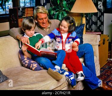70ER JAHRE LÄCHELNDER MANN VATER SITZT AUF WOHNZIMMER COUCH LESEN BUCH ZU ANIMIERTEN MÄDCHEN TOCHTER UND JUNGEN SOHN BEIDE IN ARME AUF DEM SCHOSS - KJ8468 PHT001 HARS LACHING 3 DAD RÜSTUNGSUNTERRICHT DRINNEN GESICHTER NOSTALGISCHE PAAR SUBURBAN URBAN FARBE AUSDRUCK ALTE ZEIT BESCHÄFTIGT NOSTALGIE ALTE MODE 1 JUGENDLICH GESICHTS-COUCH KOMMUNIKATION LACHEN BLONDE FRIEDEN TEAMARBEIT SÖHNE ZUFRIEDEN FAMILIEN FREUDE LIFESTYLE ELTERNSCHAFT FRAUEN GESUNDHEIT ZU HAUSE LEBEN IN VOLLER LÄNGE TÖCHTER PERSONEN PFLEGE MÄNNER AUSDRÜCKE VÄTER RUNDE ZIELE GLÜCK WELLNESS FRÖHLICH SOWOHL STÄRKE UND VÄTER GENIESSEN AUFREGUNG WISSEN STOLZ AUF AUTORITÄT GEFÜHL Stockfoto