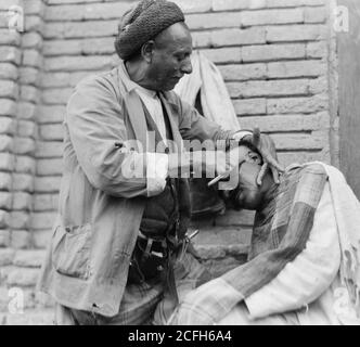 Originalunterschrift: Irak. (Mesopotamien). Bagdad. Ansicht von Straßenszenen und Typen. Straßenbarbier bei der Arbeit - Ort: Irak--Bagdad ca. 1932 Stockfoto