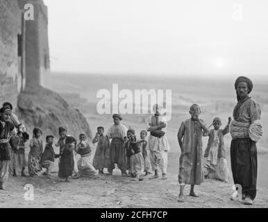 Geschichte Des Nahen Ostens - Irak. Arbela. (Erbil). Zentrum von Ishtar Kult in assyrischer Periode 2200 B.C. EIN Wüstenuntergang. Eine Gruppe von Männern und Jungen in der Dämmerung Stockfoto