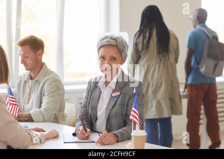 Porträt der modernen reifen Frau Registrierung Wähler während der Arbeit am Schreibtisch am Wahltag, Platz kopieren Stockfoto