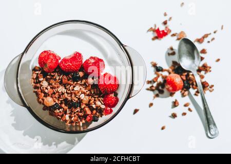 Schüssel mit hausgemachtem Müsli mit Joghurt und frischen Erdbeeren aus der Sicht von oben. Weißer Hintergrund. Gesunde Ernährung, gesunde Lebensweise Konzept. Stockfoto