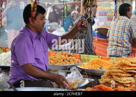 Ein Händler, der traditionelle Süßspeisen Jalebi/Jilapi in einem Geschäft eines lokalen Marktes misst. Es ist sowohl in Bangladesch als auch in Indien beliebt Stockfoto