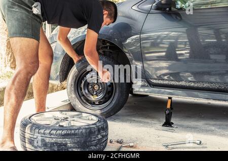Wechseln Sie einen flachen Autoreifen auf dem Parkplatz mit Reifenpflege, beschädigte Autoreifen Stockfoto