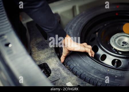 Nahaufnahme Mechaniker Hand nehmen Reserverad am Stiefel Stockfoto