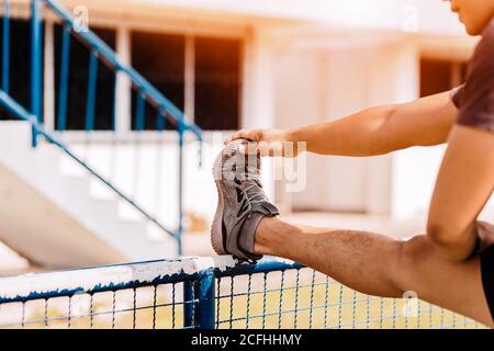 Porträt eines athletischen Mannes, der sich am Morgen im Sportstadion ausdehnt. Stockfoto
