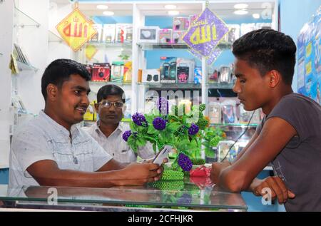 Ein Einzelhandelsverkäufer zeigt ein Handy des Kunden, Zubehör zum Verkauf in einem mobilen Shop des Vorstadtmarktes Stockfoto