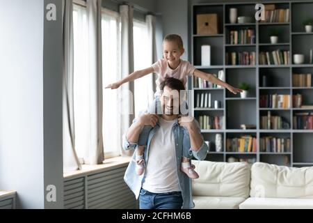 Lächelnd junger Vater hält niedliche kleine Tochter vorgeblich fliegen Stockfoto