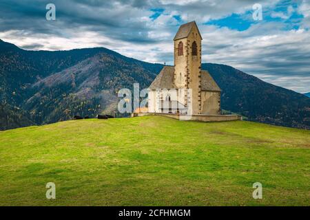 Atemberaubende Kirche St. Jakob (San Giacomo) auf dem grünen Feld. Alte Kirche mit Bergkämmen im Hintergrund, in der Nähe von Santa Maddalena Dorf in Fune Stockfoto