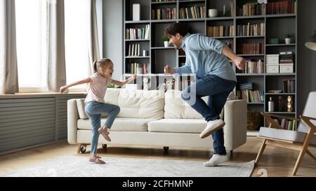 Überglücklich Vater und Tochter Spaß haben, tanzen im Wohnzimmer Stockfoto