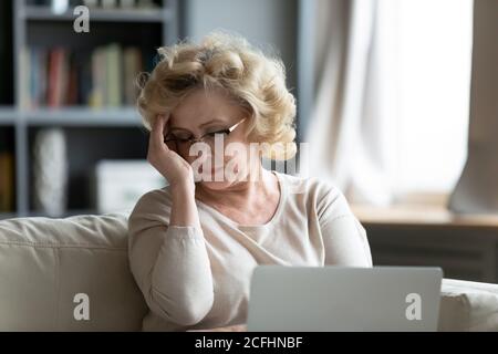 Frustrierte reife Frau trägt Brille berühren Stirn, leiden unter Kopfschmerzen Stockfoto
