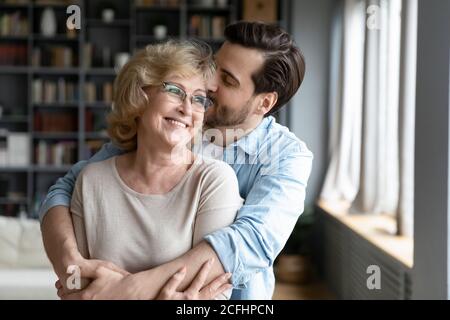Liebevolle Erwachsene Sohn küssen und umarmen glücklich reife Mutter Stockfoto