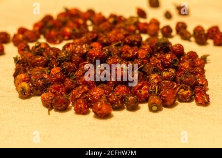 Getrocknete Hagebutten Nahaufnahme auf einer natürlichen Leinentischdecke auf dem Tisch. Stockfoto