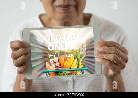 Ältere Frau, die die mobile App verwendet, um Lebensmittel zu bestellen Lebensmittel auf Online-Supermarkt für Lebensmittel Lebensmittelgeschäft Stockfoto