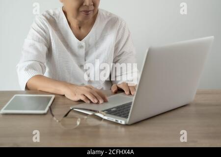 Ältere Frau mit Laptop-Computer-Tablet zu Hause Stockfoto