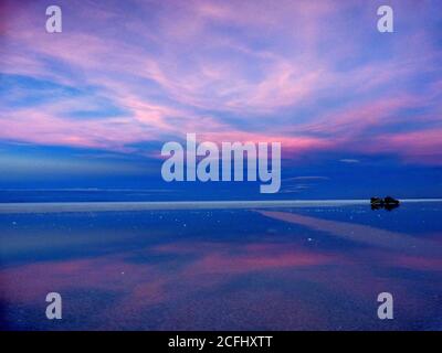 Magischer blau-rosa Sonnenuntergang. Spiegelung des Sonnenuntergangs farbigen Himmel im Salzsee. Salinen von Salar de Uyuni, Bolivien. Romantische Abendlandschaft. Stockfoto