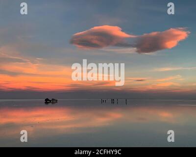 Wunderbarer Sonnenuntergang über dem malerischen Salzsee. Erstaunlicher Anblick ist die Reflexion des rosa blauen Himmels im Wasser. Romantische Natur auf Salinen Salar de Uyuni. Stockfoto