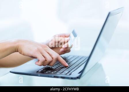 Online-Buchung Zahlung und Banking-Transaktion. Nahaufnahme der Hände einer Person, die eine Kreditkarte hält und Kontoinformationen auf einem Laptop-Computer eingibt. Stockfoto