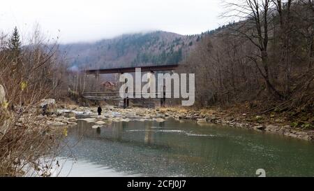 Blick auf die Eisenbahnbrücke über den Fluss Prut. Eine kleine Stadt oder Dorf Yaremche unter den Karpaten an einem Herbstnachmittag. Ukraine, Jaremcha - Stockfoto