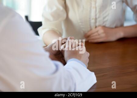 Nahaufnahme fürsorglicher Arzt hält junge Frau Hand, Empathie Konzept Stockfoto