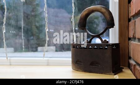 Altes Gusseisen zum Bügeln der Wäsche. Auf der Fensterbank befinden sich Wohnaccessoires aus dem letzten Jahrhundert als Dekor im Restaurantinnenraum. Rostig Stockfoto