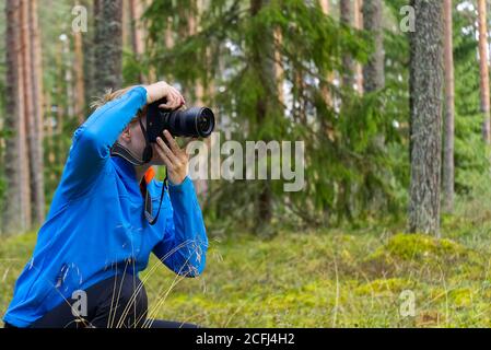 Junge Frau Trekking zwischen Bäumen und fotografieren mit der Kamera. Frau mittleren Alters Fotografin fotografieren im Herbst Wald. Naturfotografie. Stockfoto