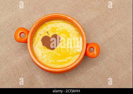 Hausgemachter süßer Maispudding in Brasilien als Curau oder Canjica Nordestina in Keramikschale bekannt. Zimtpulver in Herzform. Stockfoto