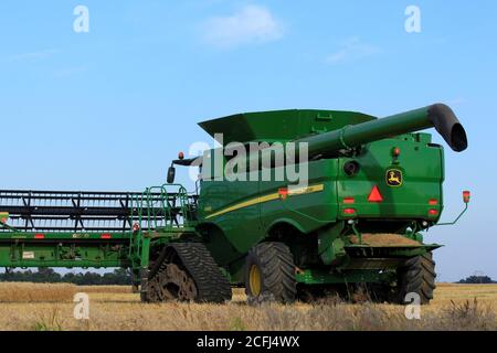 John Deere Kombinieren Sie das Schneiden von Weizen in einem landwirtschaftlichen Feld in Kansas auf dem Land mit blauem Himmel. Stockfoto