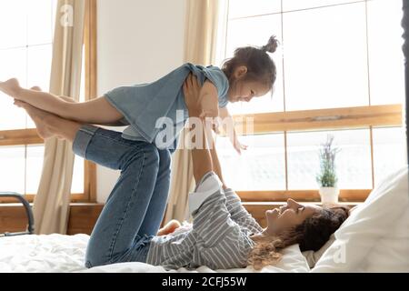 Mutter hält Tochter auf ausgestreckten Armen Kind fliegen in der Luft Stockfoto