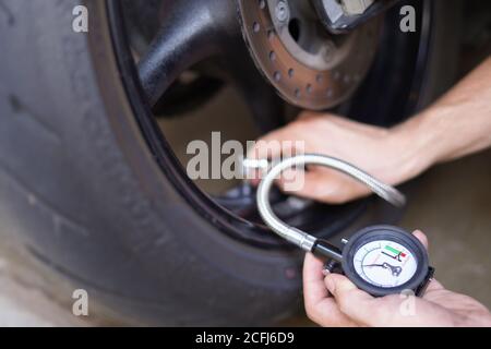 Der Mann überprüft den Luftdruck des Motorrades vor der Fahrt manuell Stockfoto