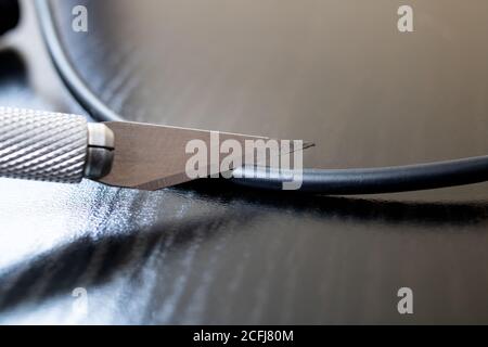 Schneiden Sie dicken Draht mit einem technischen Skalpell Stockfoto