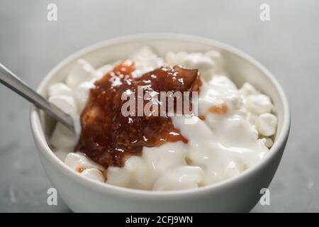 Quark mit Feigenmarmelade in weißer Schale auf Betongrund, flacher Fokus Stockfoto