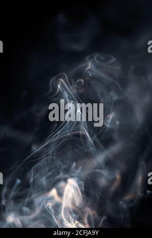 Weißer Rauch von Räucherstäbchen isoliert vor dunklem Hintergrund Stockfoto