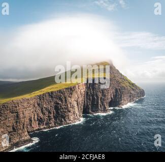 Färöer Inseln Traelanipa die Slaves Felsen Klippe wird gesehen, steigt über dem Ozean neben See Sorvagsvatn. Wolken und blauer Himmel während suommer auf dem Stockfoto