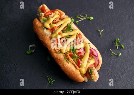 Klassischer Hot Dog mit Ketchup und Senf auf einem schwarzen Hintergrund Stockfoto