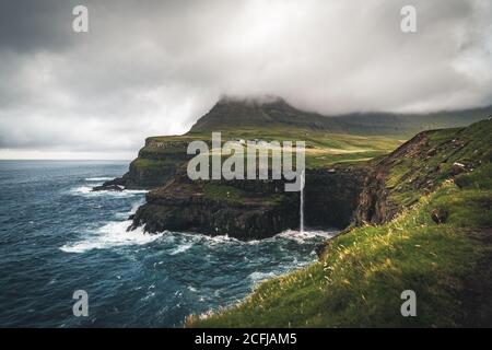 Luftdrohnenpanorama von Gasadalur Dorf und Mulafossur seinen ikonischen Wasserfall, Vagar, Färöer Inseln, Dänemark. Raue See im nordatlantik Ozean Stockfoto