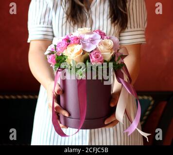 Box mit Blumen mit Band in Mädchen Hände Stockfoto