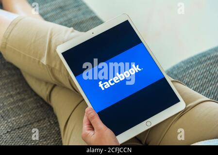 Frau Hände mit iPad mit Facebook-Homepage auf dem Bildschirm. Facebook das größte soziale Netzwerk Webseite. Stockfoto