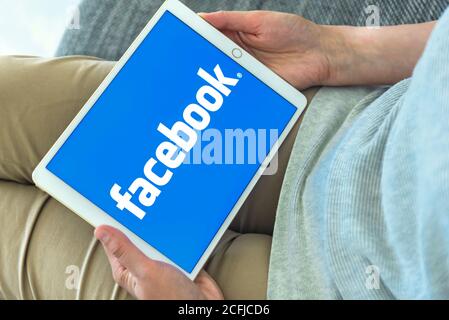 Frau Hände mit iPad mit Facebook-Homepage auf dem Bildschirm. Facebook das größte soziale Netzwerk Webseite. Stockfoto