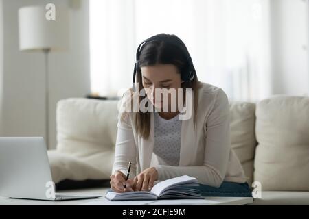 Junge Dame im schnurlosen Headset hört Online-Lehrvortrag. Stockfoto