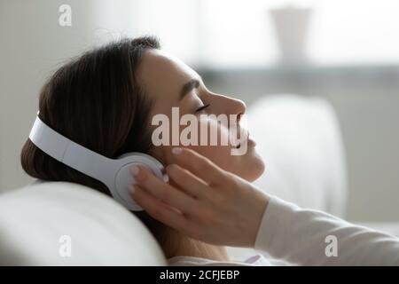 Friedliche junge Frau, die in Kopfhörern inspirierende Lieblingsmusik hört. Stockfoto