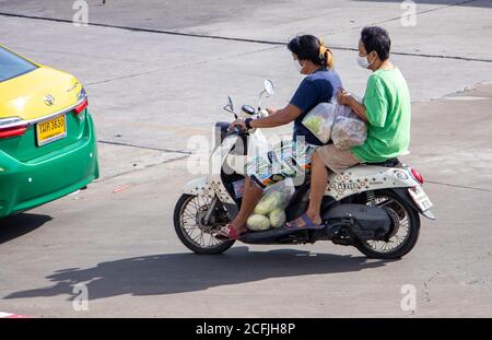 SAMUT PRAKAN, THAILAND, JUNI 26 2020, zwei Frauen mit vielen Plastiktüten von Marktfahrten auf dem Motorrad auf der Straße. Stockfoto