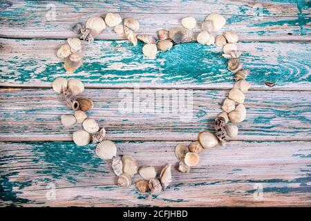 Muscheln in Herzform auf blauem Holzhintergrund. Kopieren Sie Spaes Stockfoto